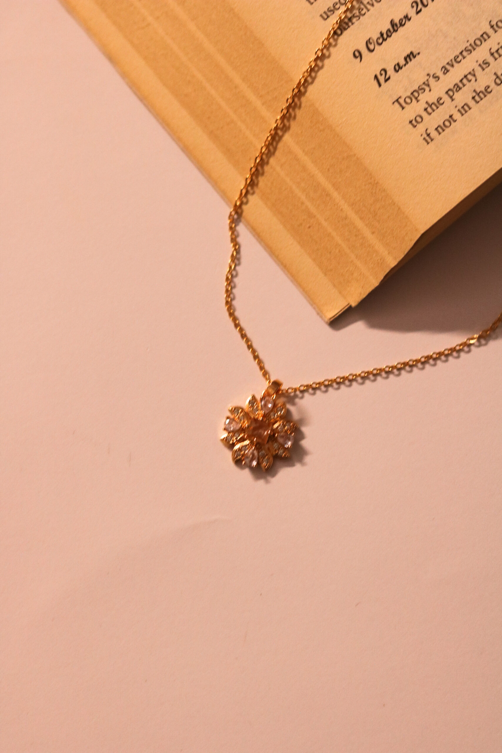 Blooming sparkle in gold-tone—a delicate floral pendant necklace that whispers elegance with every petal