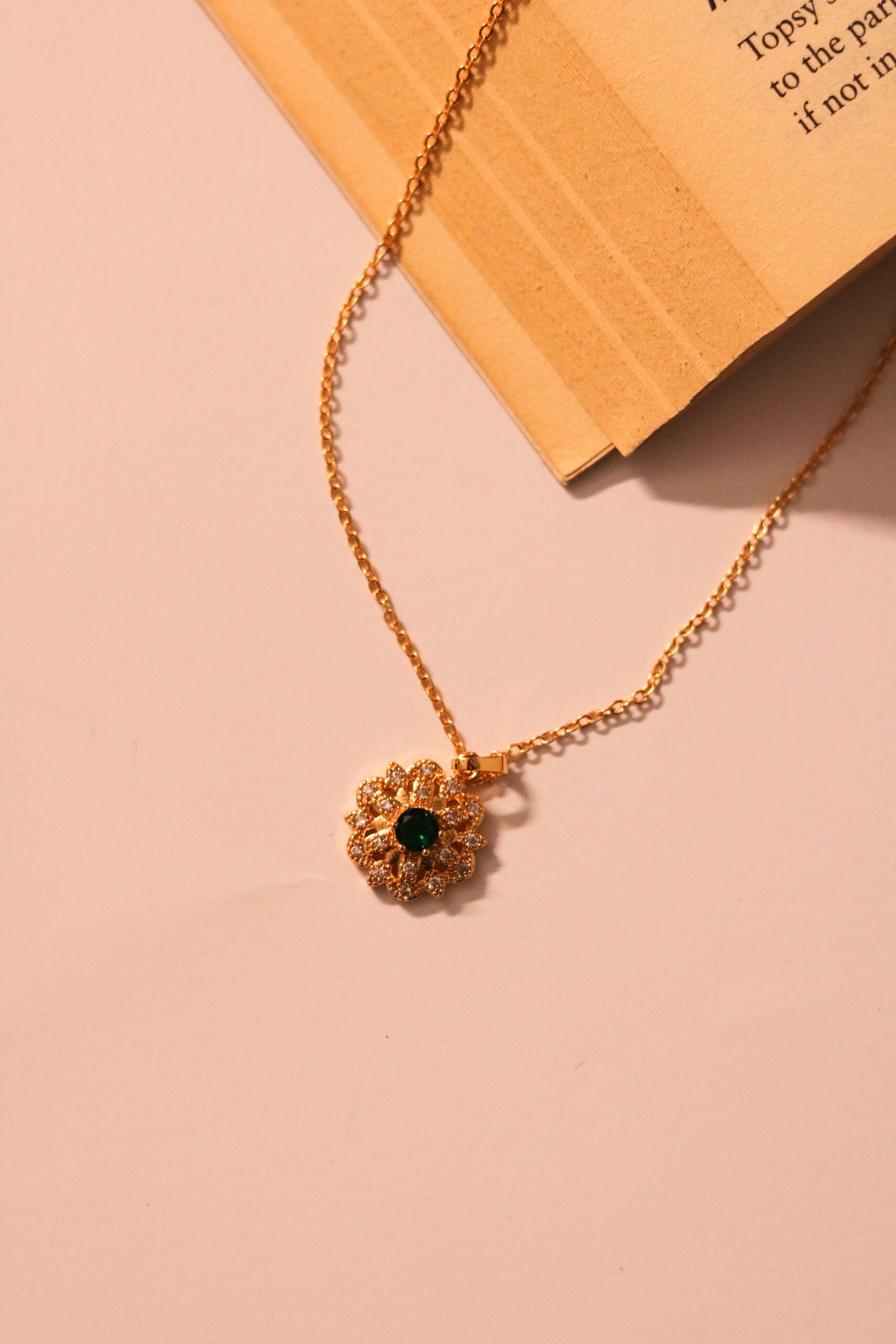 Emerald blooms on golden prose—a necklace that reads like poetry
